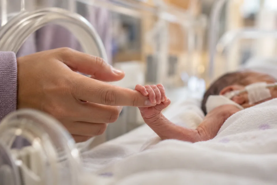 Cena ilustrativa da mão de um bebê prematuro segurando o dedo de um adulto